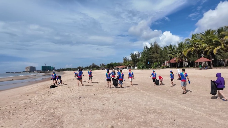 Toàn cảnh hoạt động nhặt rác biển với nhiều nhóm tham gia tại khu vực bãi biển và resort
